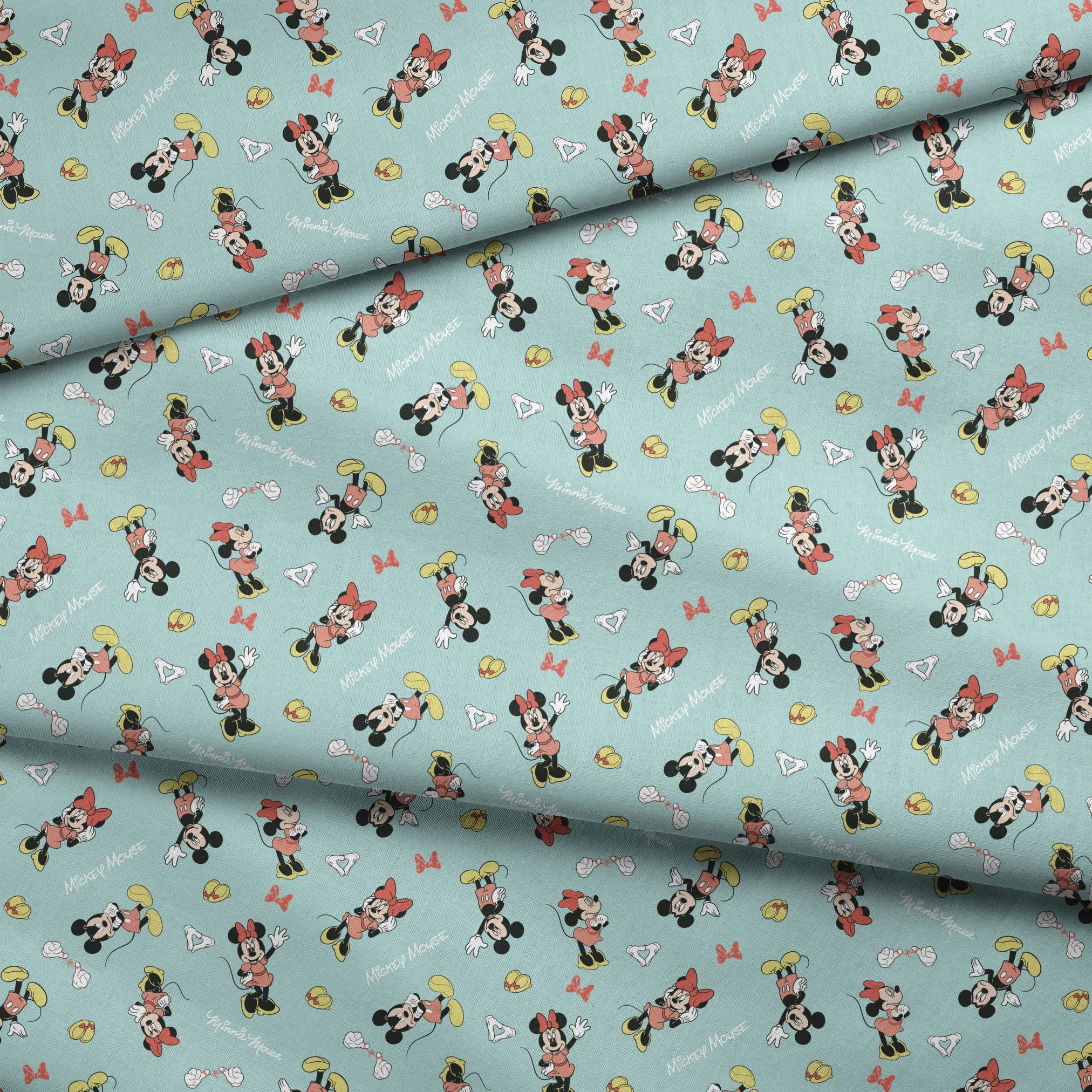 Mickey and Minnie Mouse pattern on light turquoise background with scattered characters, bows, and gloves fabric fold mockup