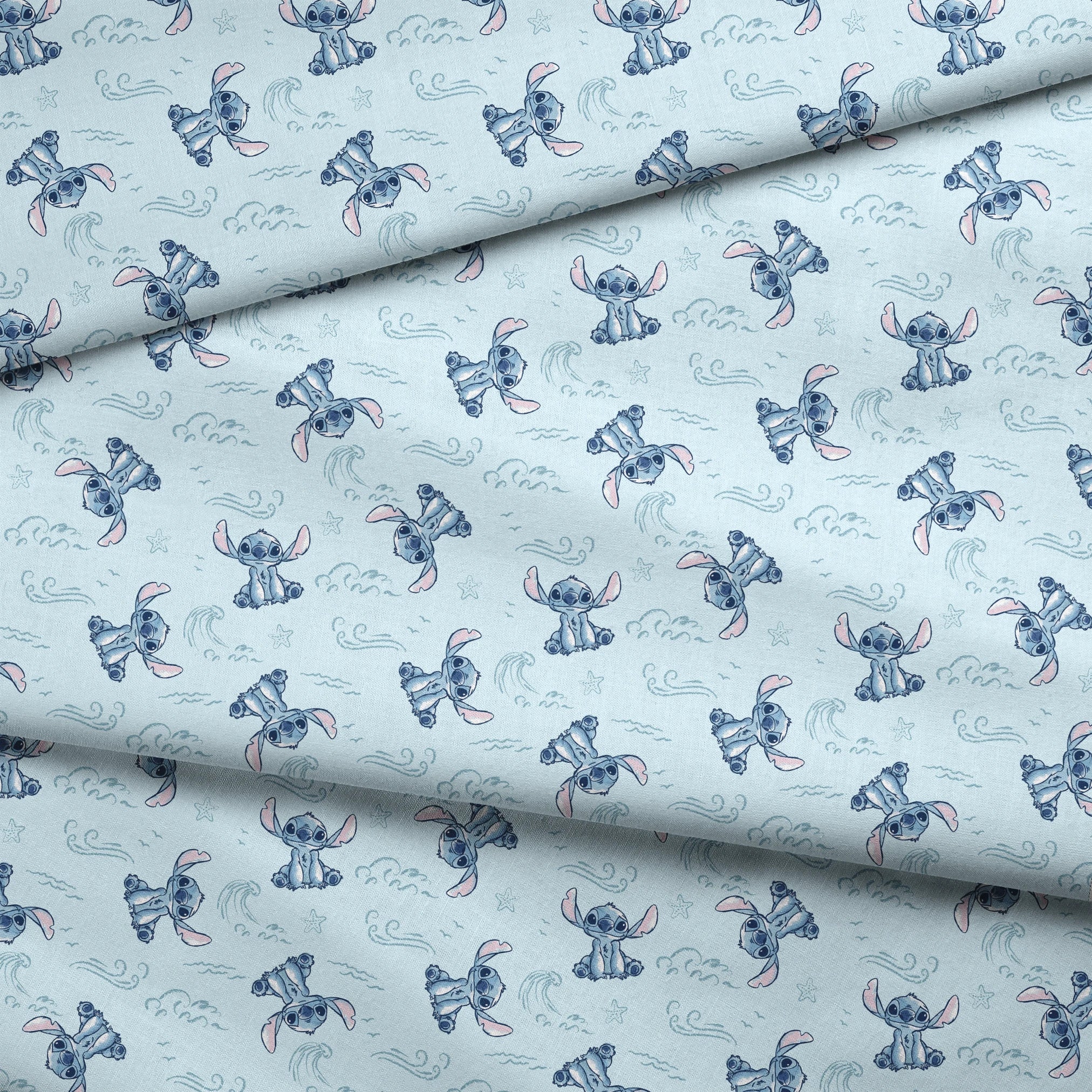 Blue cartoon alien characters with large ears in playful poses against light blue background with swirls and stars pattern fabric fold mockup