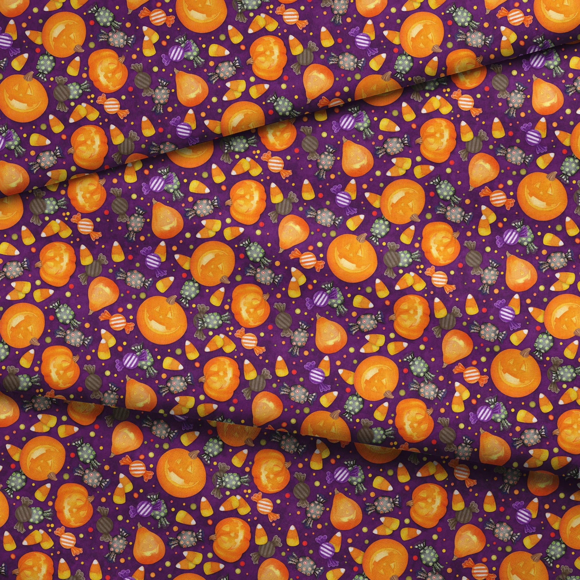 Playful Halloween fabric design by Nicole Tamarin featuring smiling jack-o’-lanterns, wrapped candies, and candy corn scattered across a purple background. fabric fold mockup