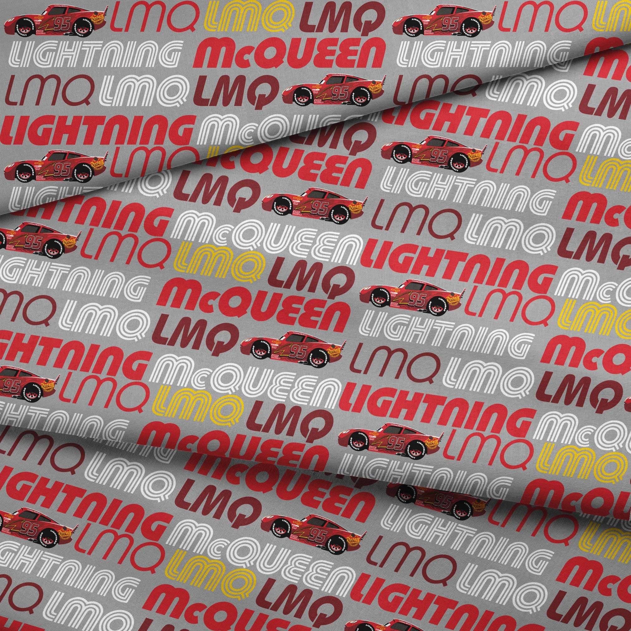 Lightning McQueen race car graphic with repeating LMQ text in red, yellow, and white on gray background fabric fold mockup