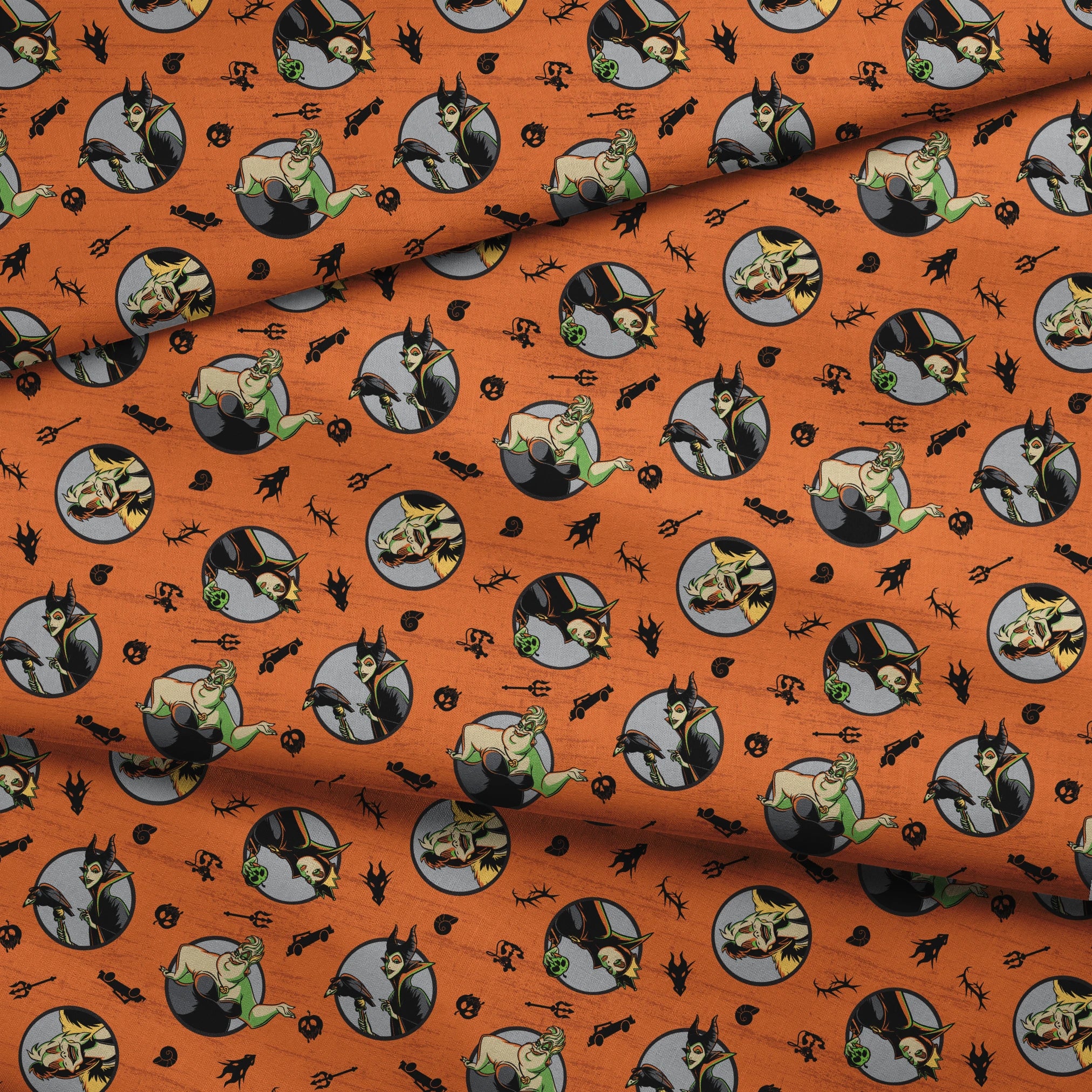 Halloween-themed orange pattern with circular Disney Villain portraits, black cats, bats, pumpkins, and spooky symbols fabric fold mockup