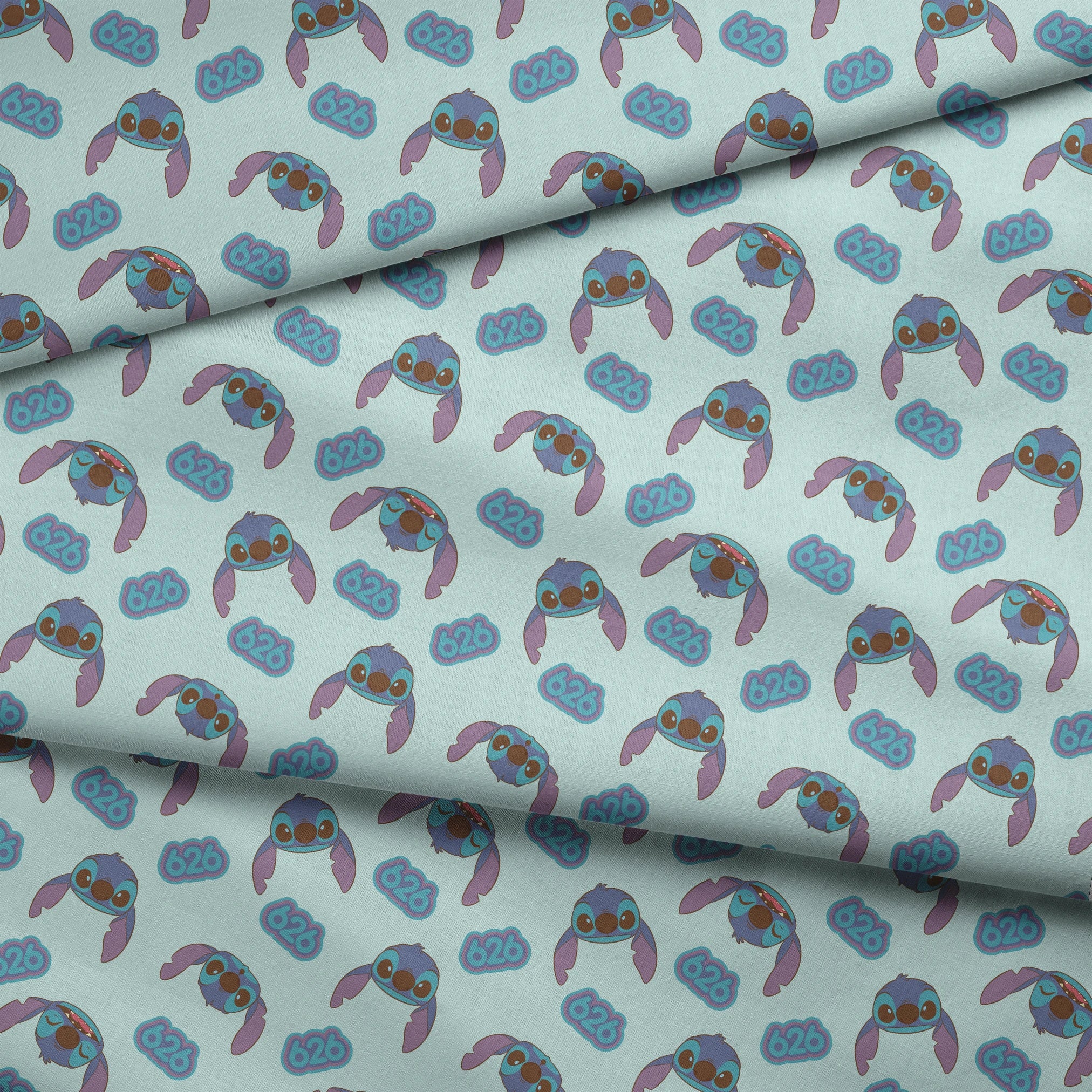 Blue cartoon creatures with large ears and swirl patterns on light teal background fabric fold mockup
