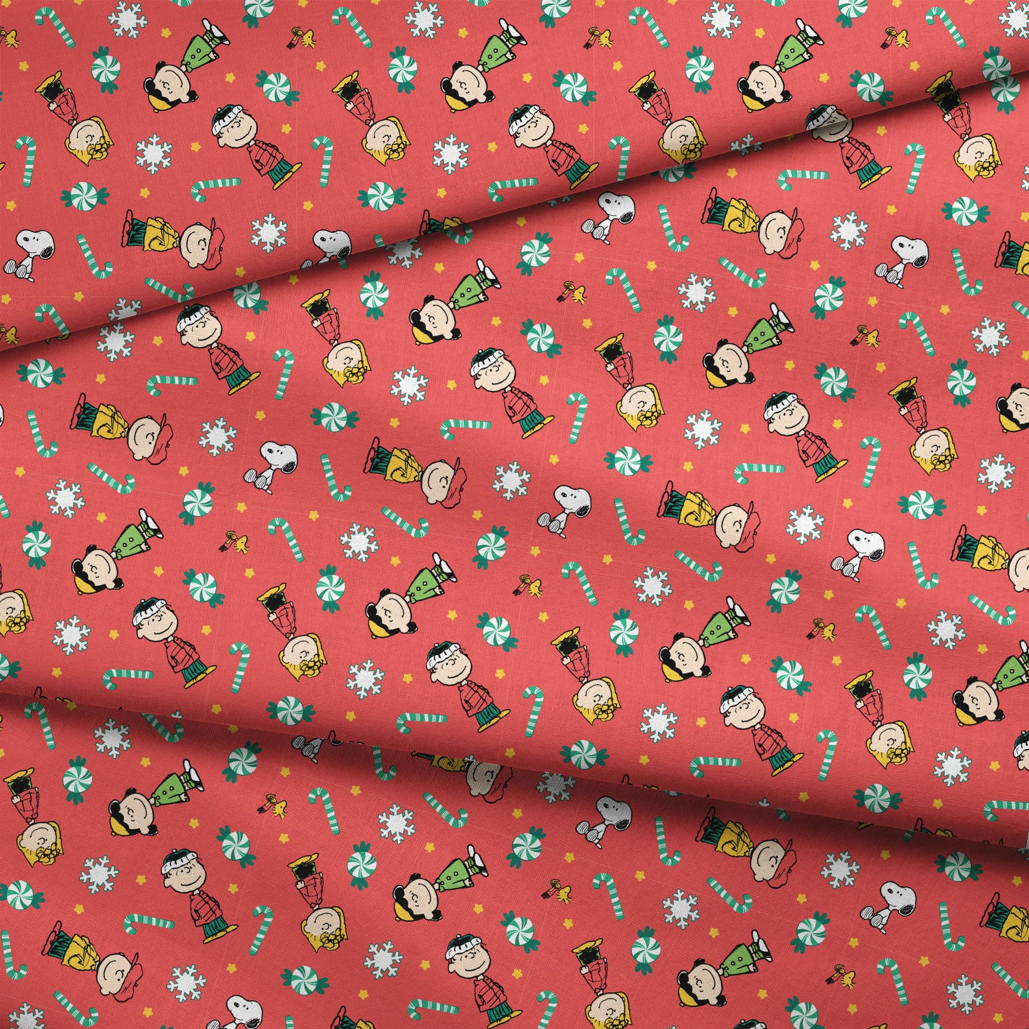 Festive Peanuts cartoon pattern with Charlie Brown characters, candy canes, snowflakes, and peppermints on red background fabric fold mockup