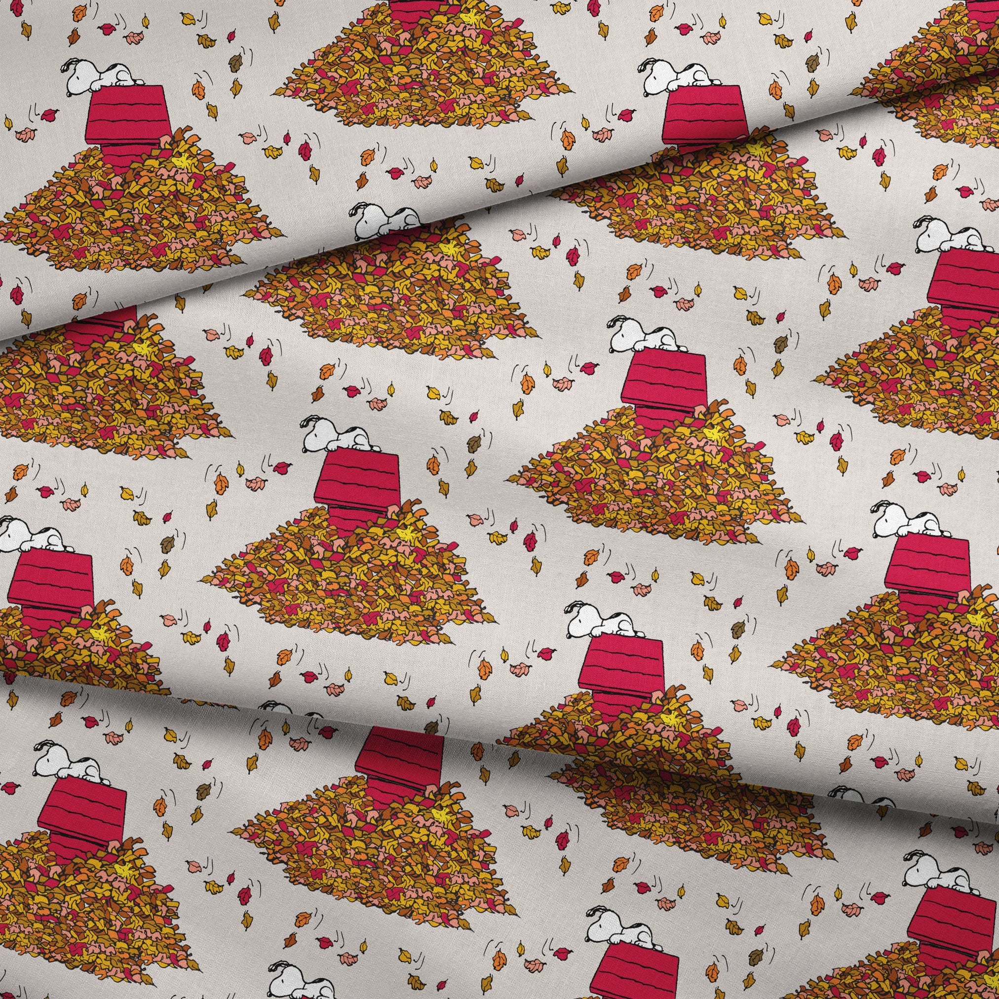 Snoopy and red doghouse on colorful autumn leaf piles with falling leaves pattern on beige background fabric fold mockup
