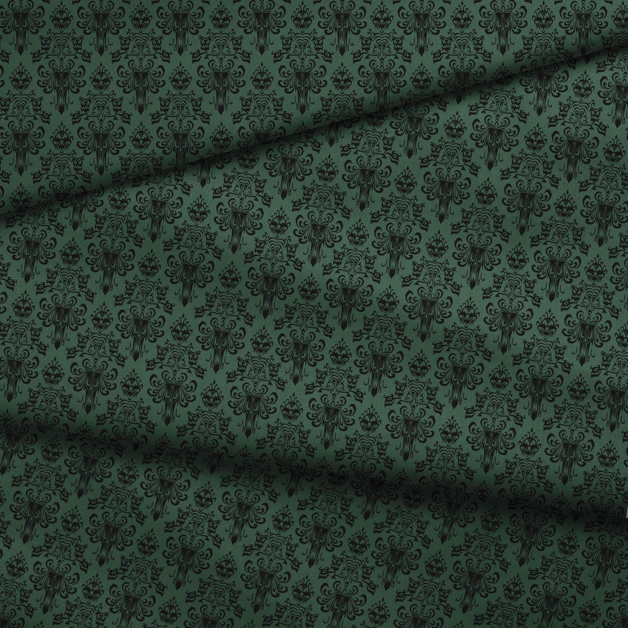 The image shows an elegant Victorian or Gothic-style damask pattern in black against a dark green background. The repeating ornate design features intricate scrollwork, flourishes, and symmetrical decorative elements arranged in a traditional wallpaper or textile pattern style. fabric fold mockup