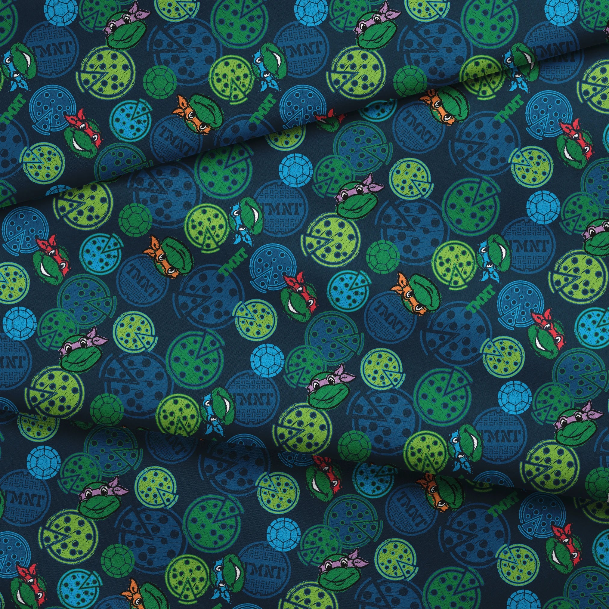Teenage Mutant Ninja Turtles pattern with cartoon character heads and green/blue pizza circles fabric fold mockup