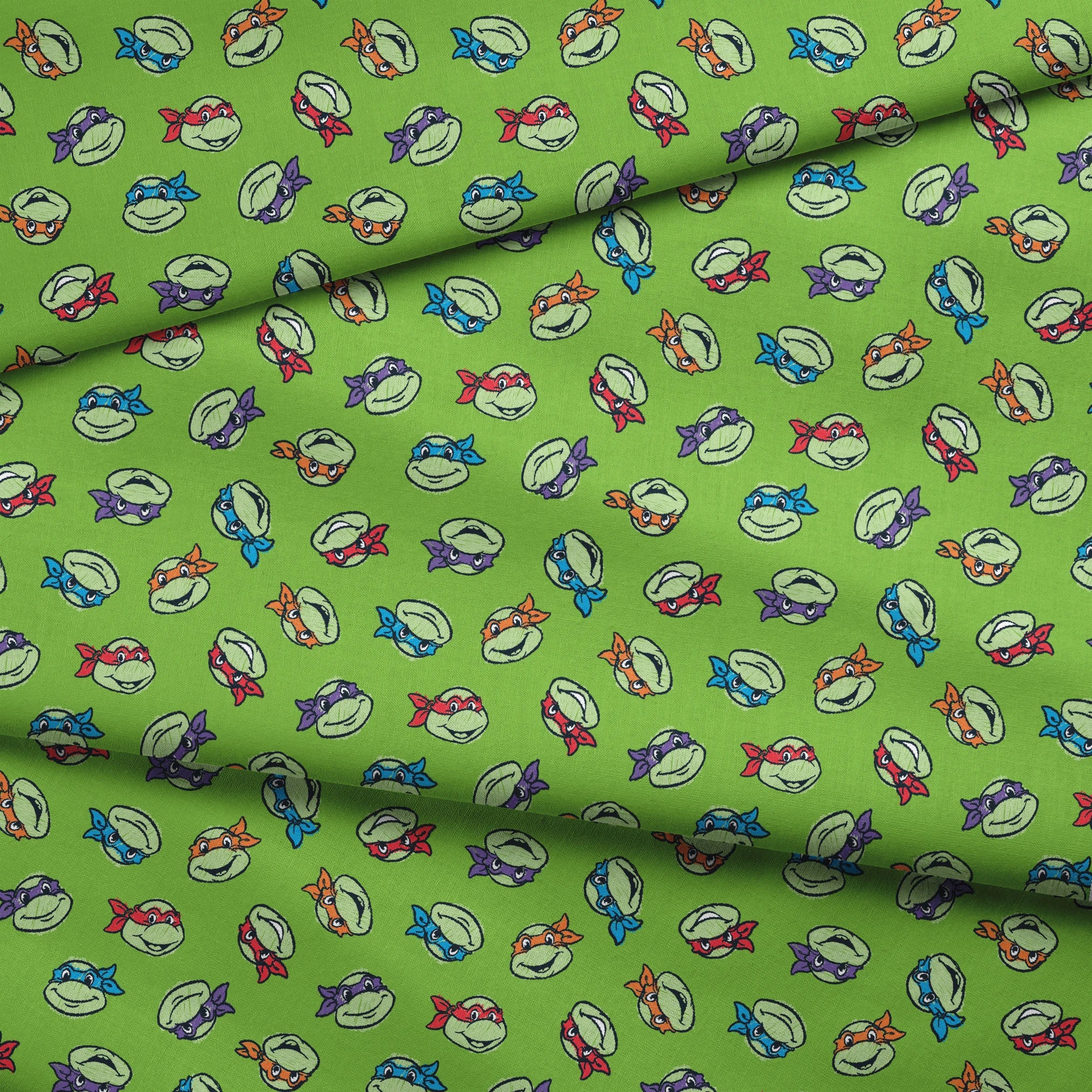 Teenage Mutant Ninja Turtles scattered on bright green background fabric fold mockup
