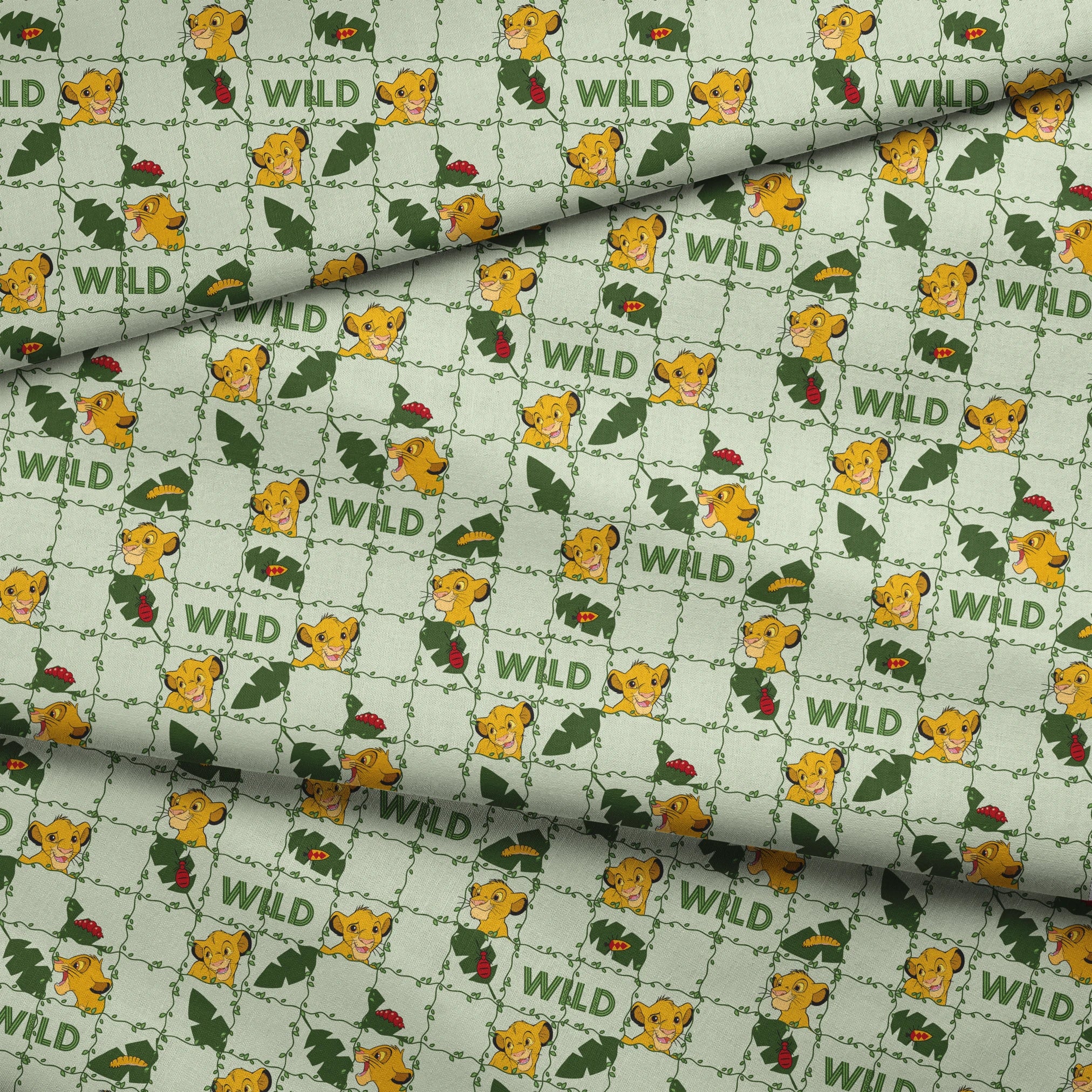 Young cartoon lion cubs with tropical leaves and "WILD" text on light green background pattern fabric fold mockup