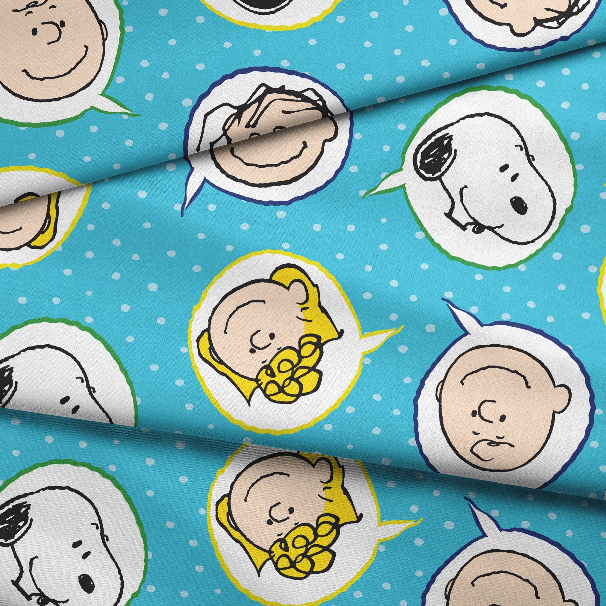 Peanuts characters pattern with Snoopy and other cartoon faces in circles on blue background fabric fold mockup