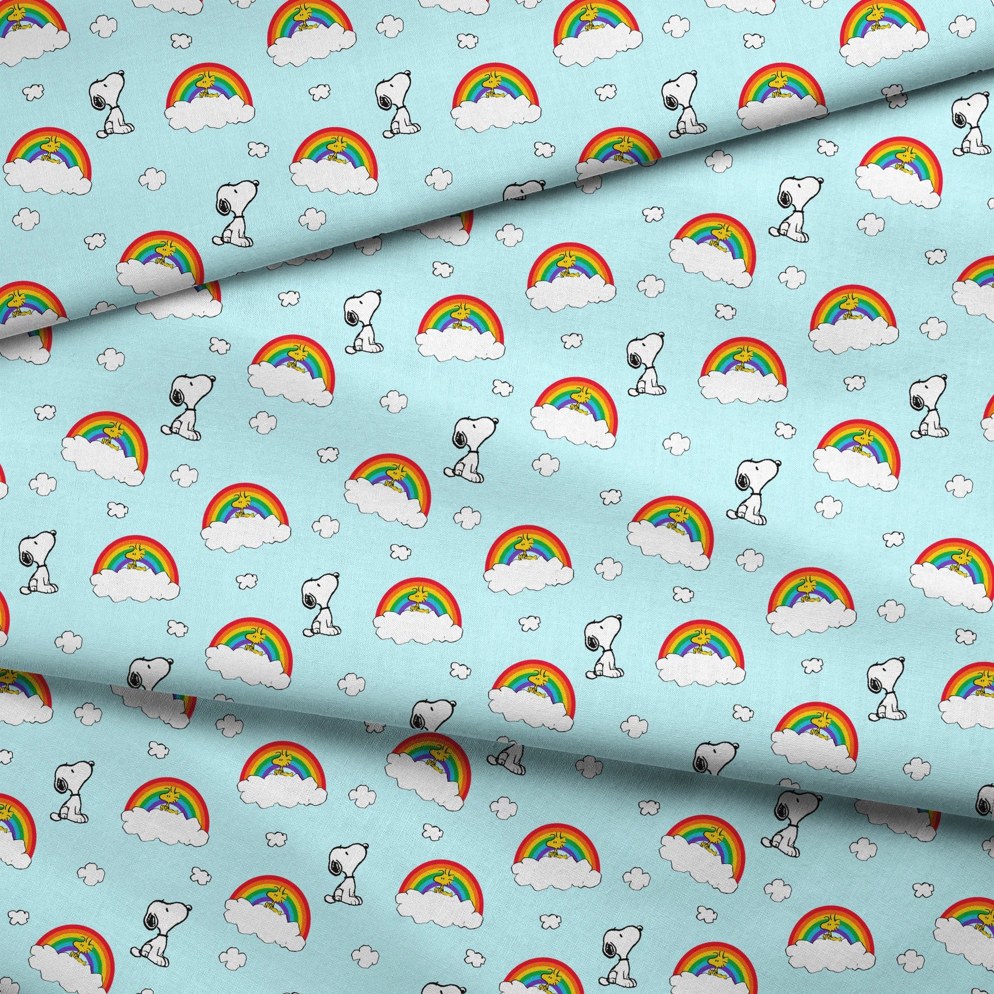 Snoopy and Woodstock characters on light blue background with rainbows, clouds and white fluffy clouds fabric fold mockup