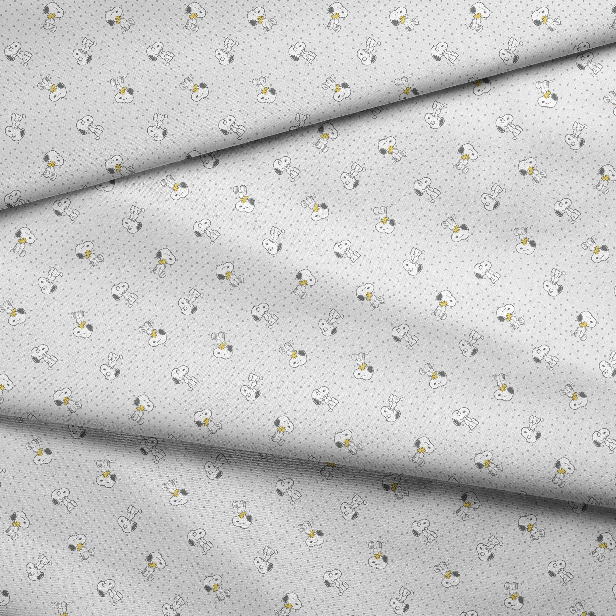 Snoopy and Woodstock on polka dot background in a repeating pattern fabric fold mockup