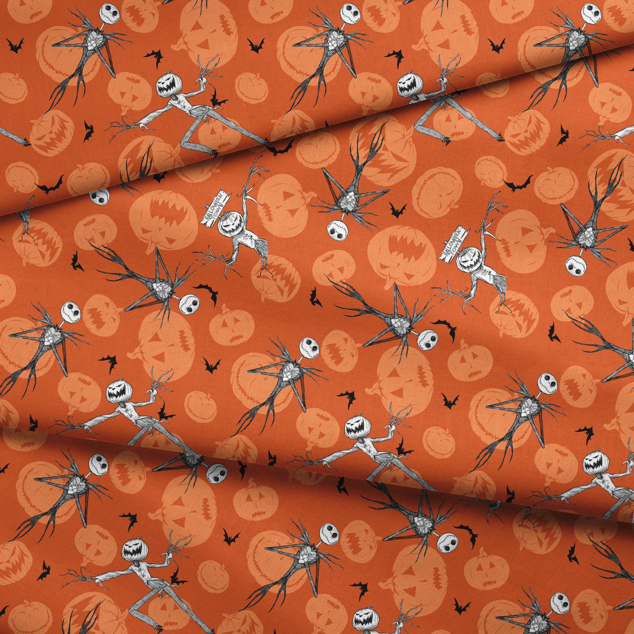 Nightmare Before Christmas pattern with Jack Skellington, bats, and jack-o'-lantern silhouettes on orange background fabric fold mockup