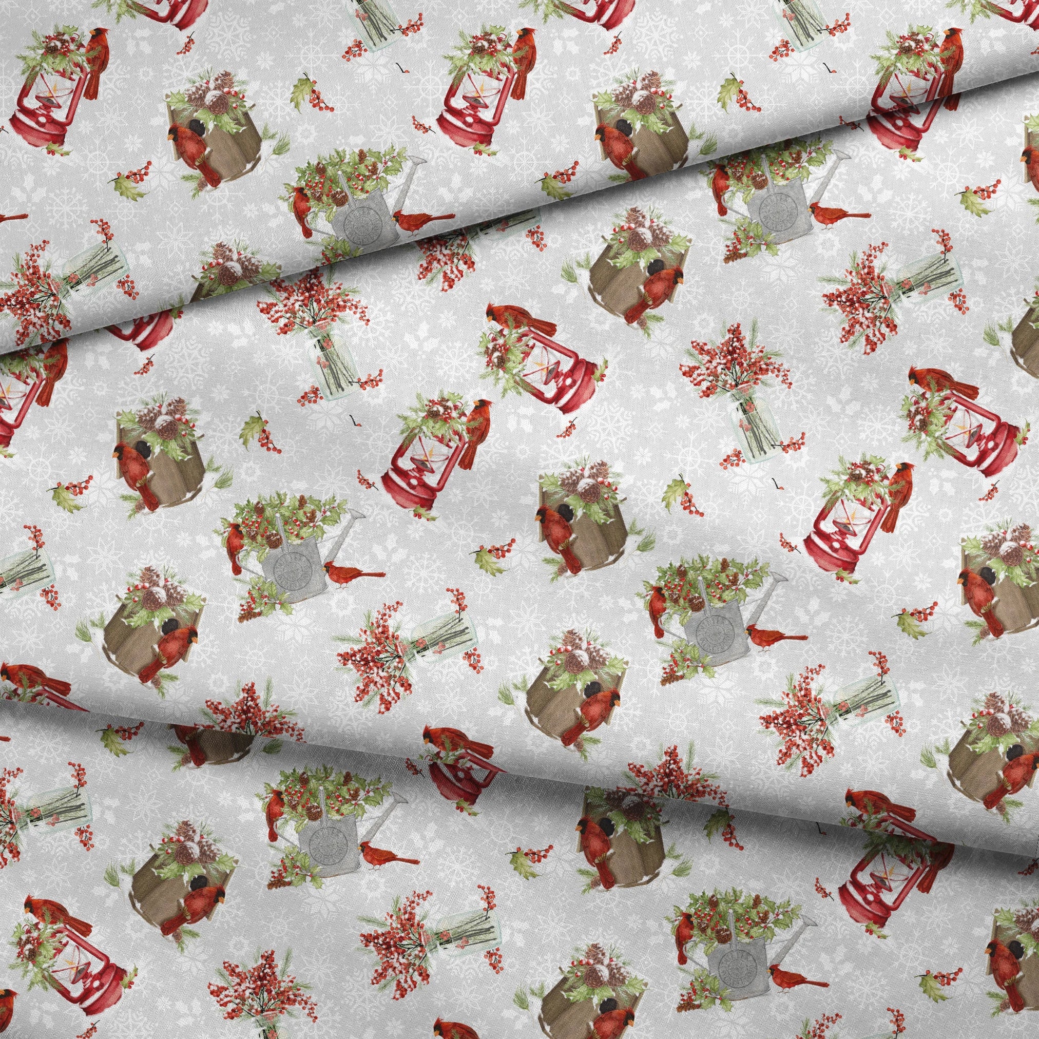 Red cardinals perched among holly berries, pine sprigs, lanterns, and rustic containers on a soft snowy background with snowflake details by Nicole Tamarin fabric fold mockup