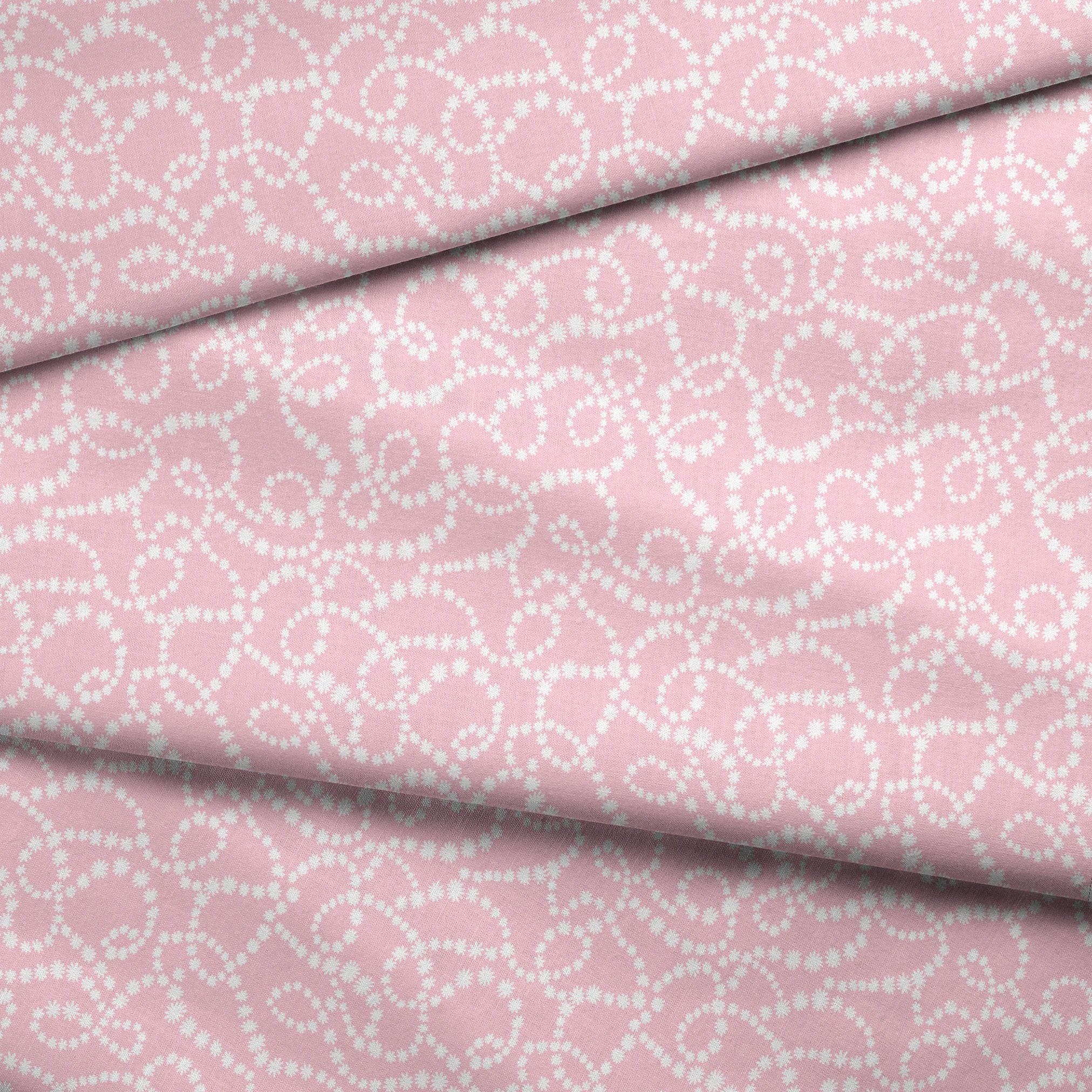 Baby pink background with white dotted swirling pattern creating delicate curved lines and loops fabric fold mockup