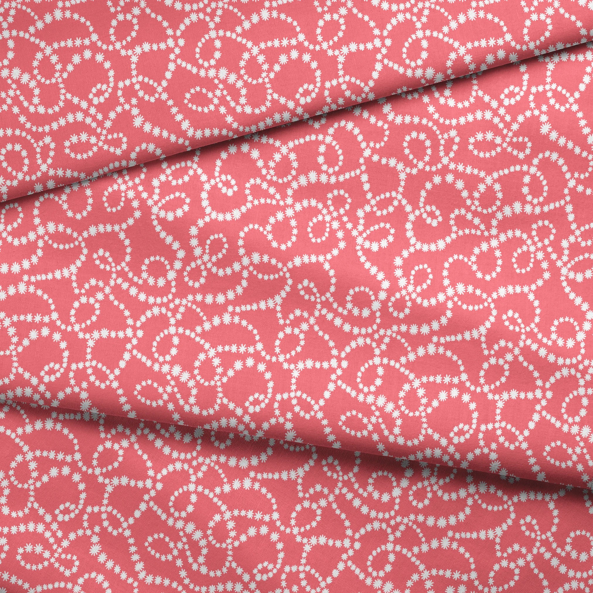 White dot patterns forming swirling chains on coral pink background fabric fold mockup