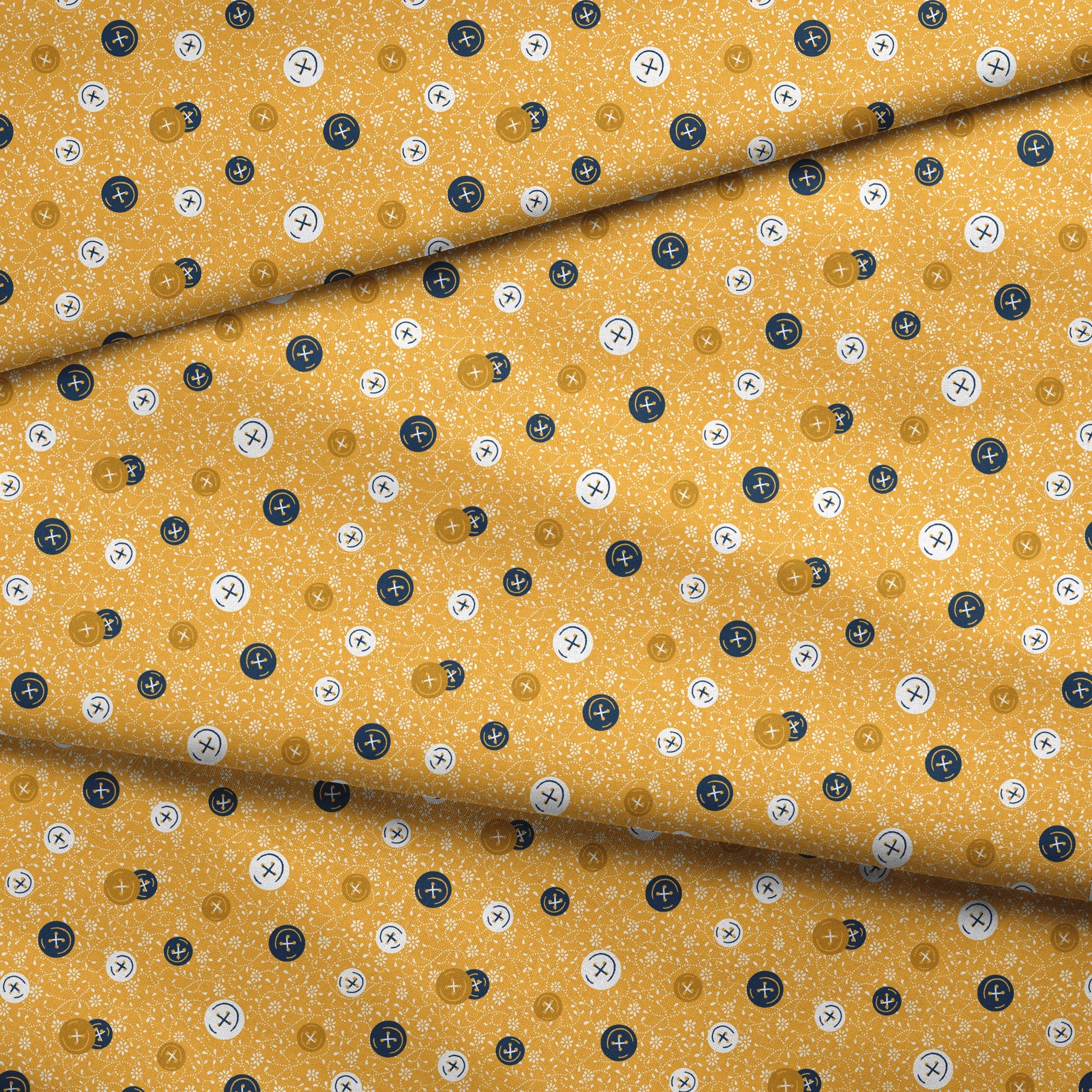 Circular buttons with cross symbols in gold, navy, and white scattered on a gold floral background fabric fold mockup