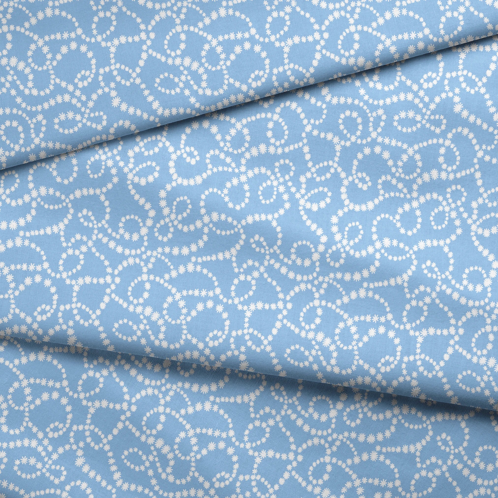 Pale blue background with white dotted swirling pattern resembling strings of pearls or bubbles in abstract curves fabric fold mockup