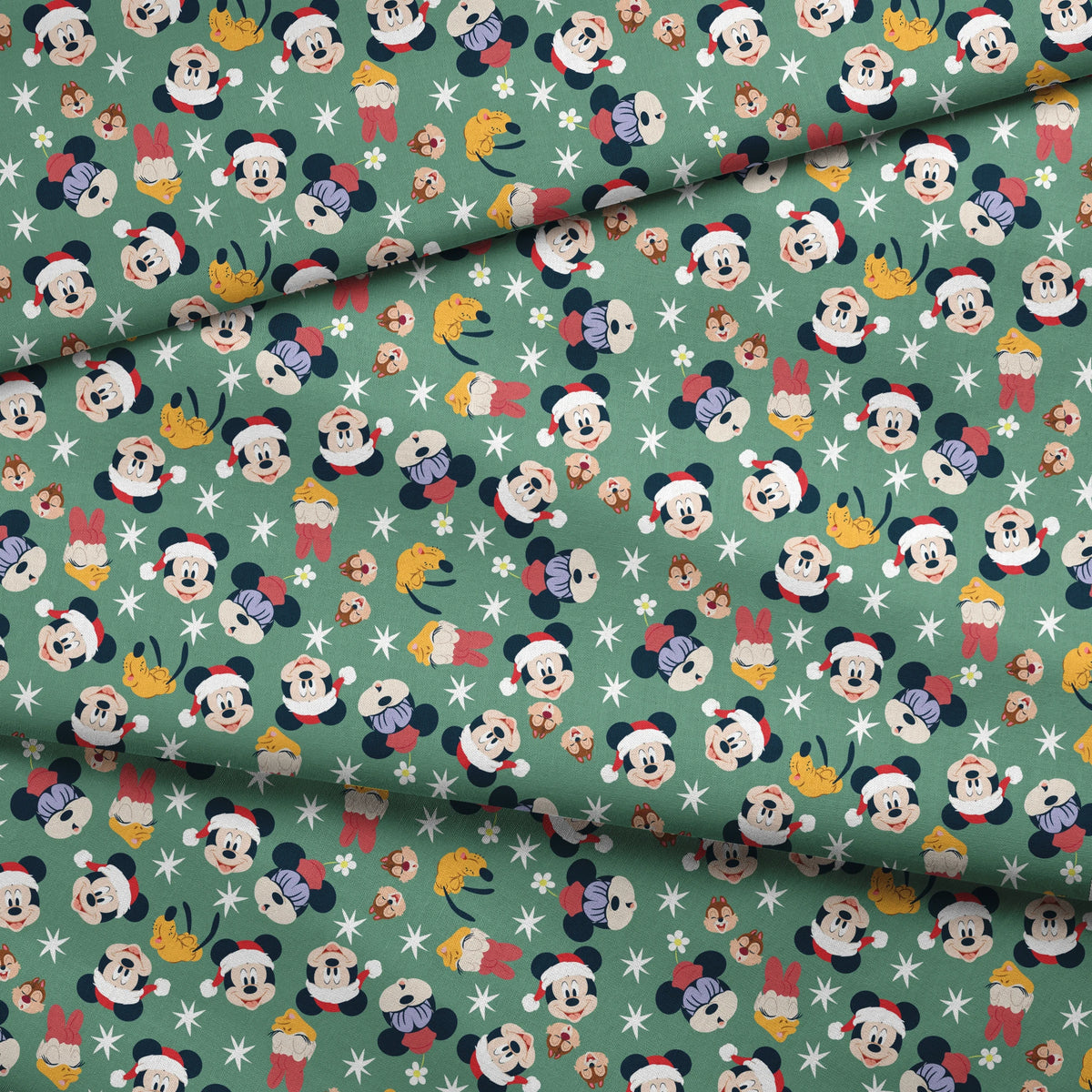 Mickey Mouse holiday pattern with characters wearing Santa hats on green background with stars and ornaments fabric fold mockup