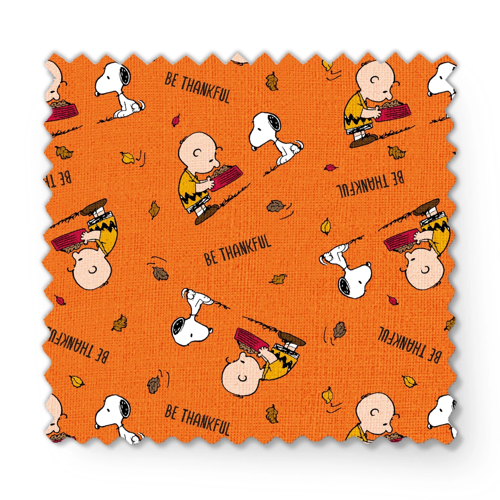 Peanuts characters on orange background with autumn leaves and "Be Thankful" text pattern fabric swatch mockup