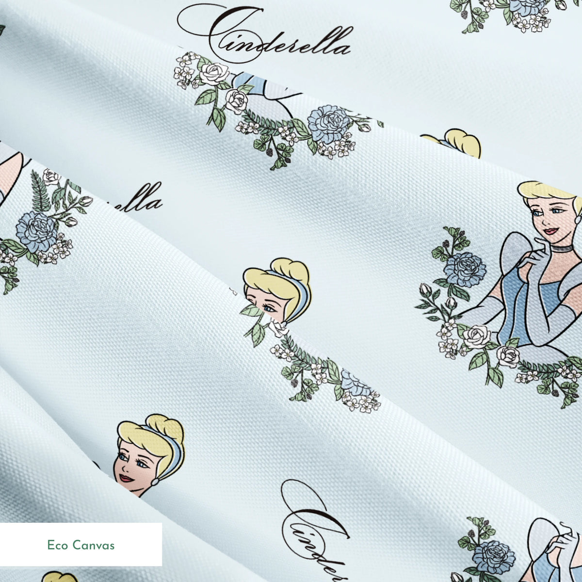 The image shows a pattern featuring a cartoon princess character in a blue dress surrounded by decorative green wreaths on a light blue background. The word "Cinderella" appears in cursive script throughout the design. springs ecocanvas texture