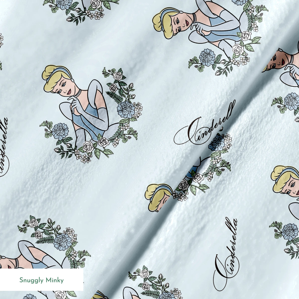 The image shows a pattern featuring a cartoon princess character in a blue dress surrounded by decorative green wreaths on a light blue background. The word "Cinderella" appears in cursive script throughout the design. springs minky texture