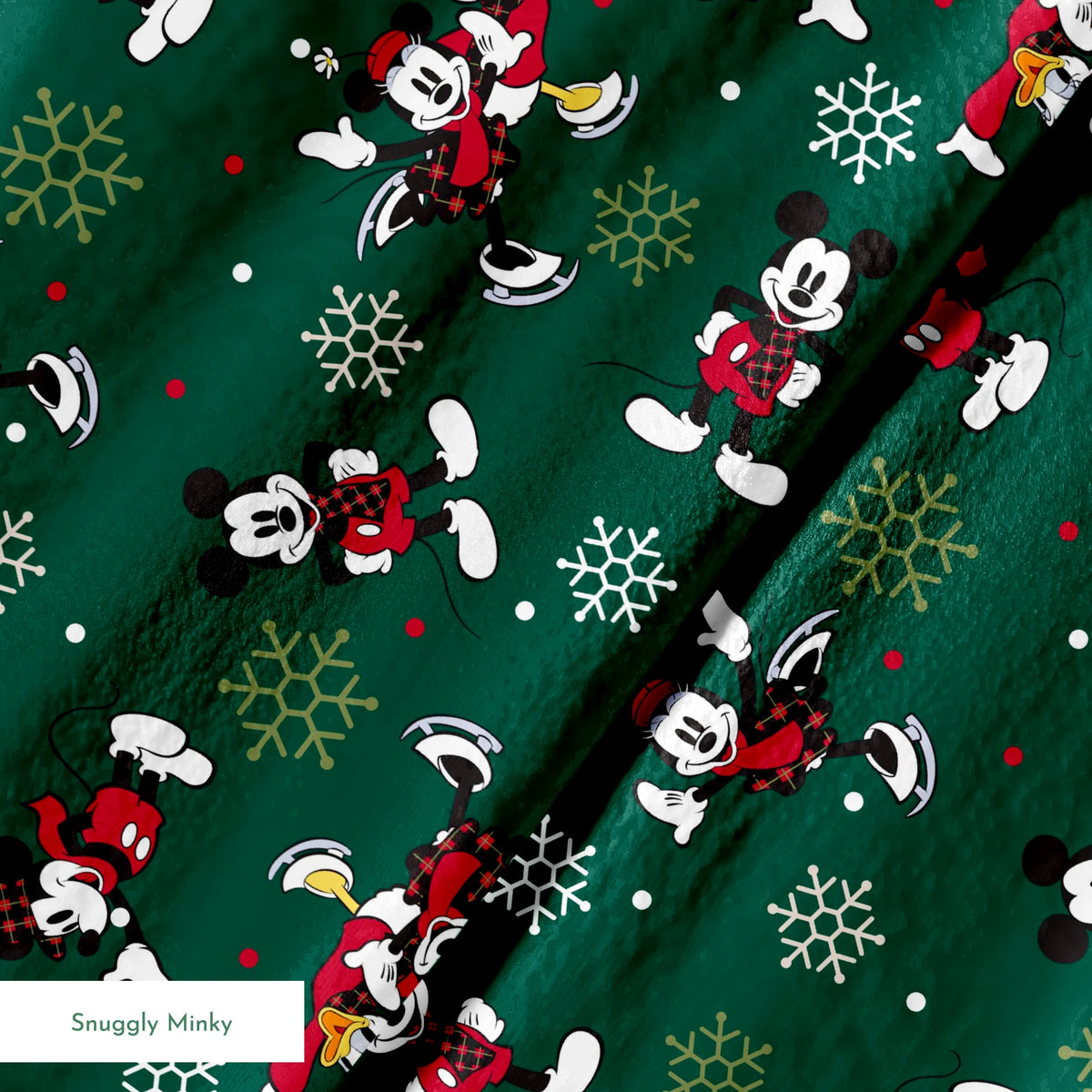 Mickey Mouse Christmas pattern with cartoon characters in winter outfits on green background with snowflakes springs minky texture