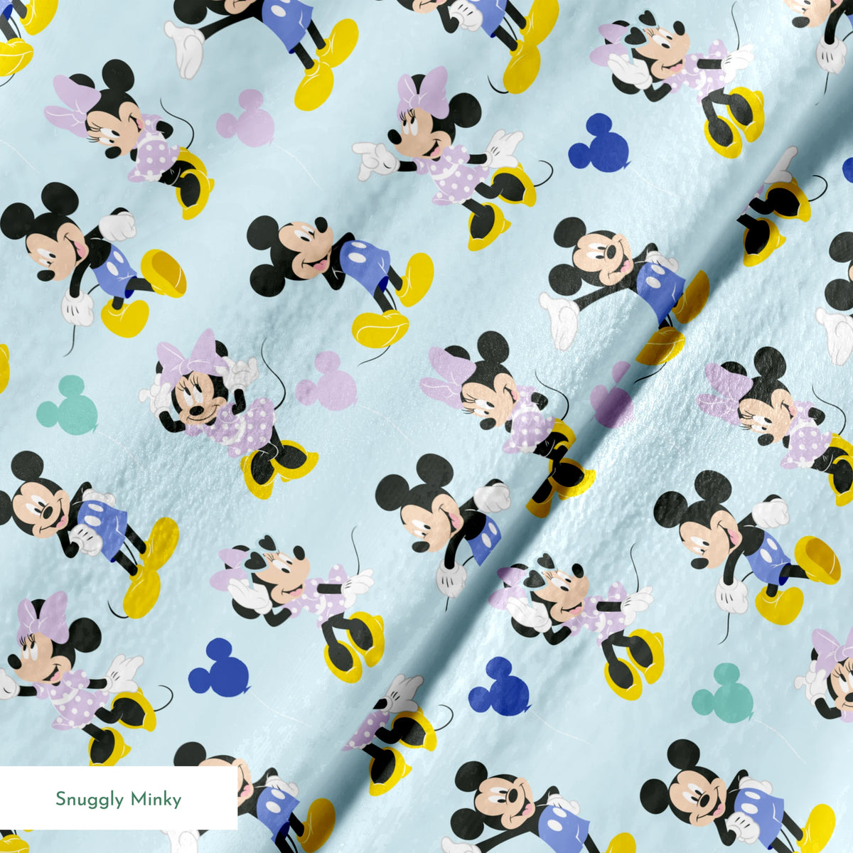 Pattern of Mickey and Minnie Mouse characters in various poses on light blue background springs minky texture