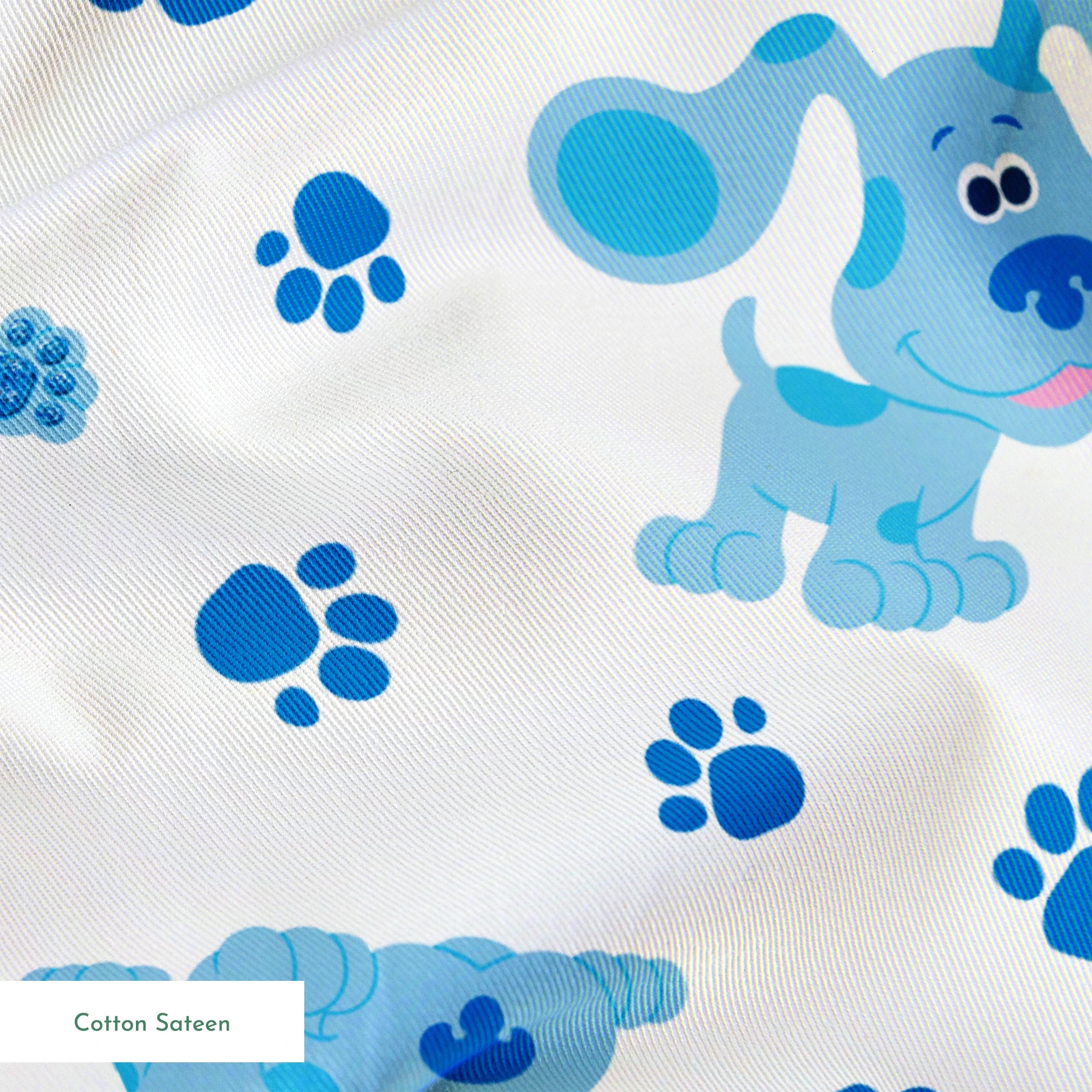 Blue cartoon puppies with floppy ears scattered among paw print pattern on white background springs sateen texture