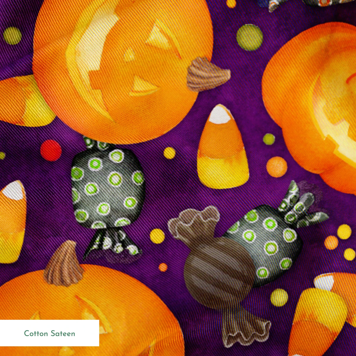Playful Halloween fabric design by Nicole Tamarin featuring smiling jack-o’-lanterns, wrapped candies, and candy corn scattered across a purple background. springs sateen texture