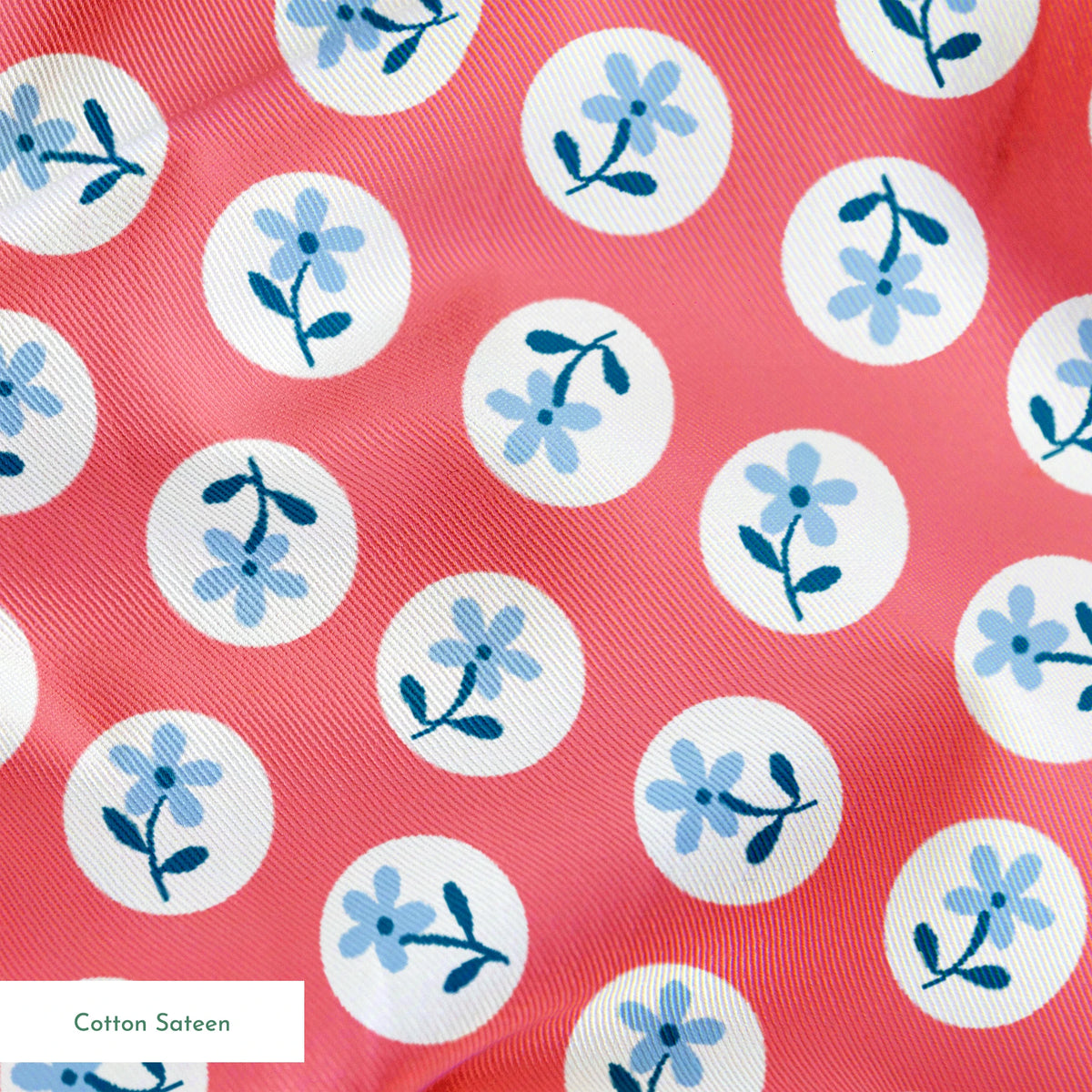 Coral pink background with white circles containing light blue floral designs arranged in a pattern springs sateen texture