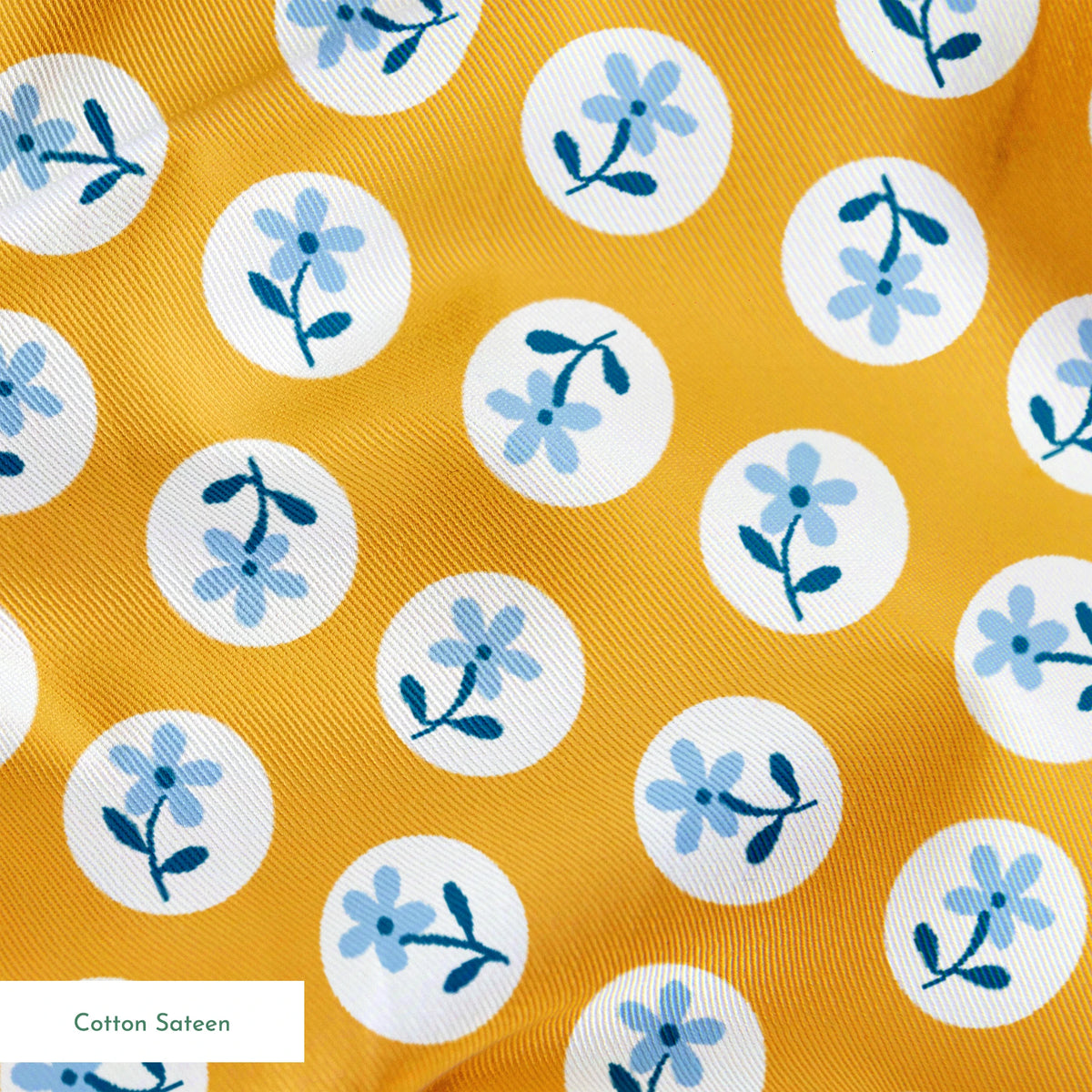 Light blue flowers with navy stems in white circles on a mustard yellow background springs sateen texture