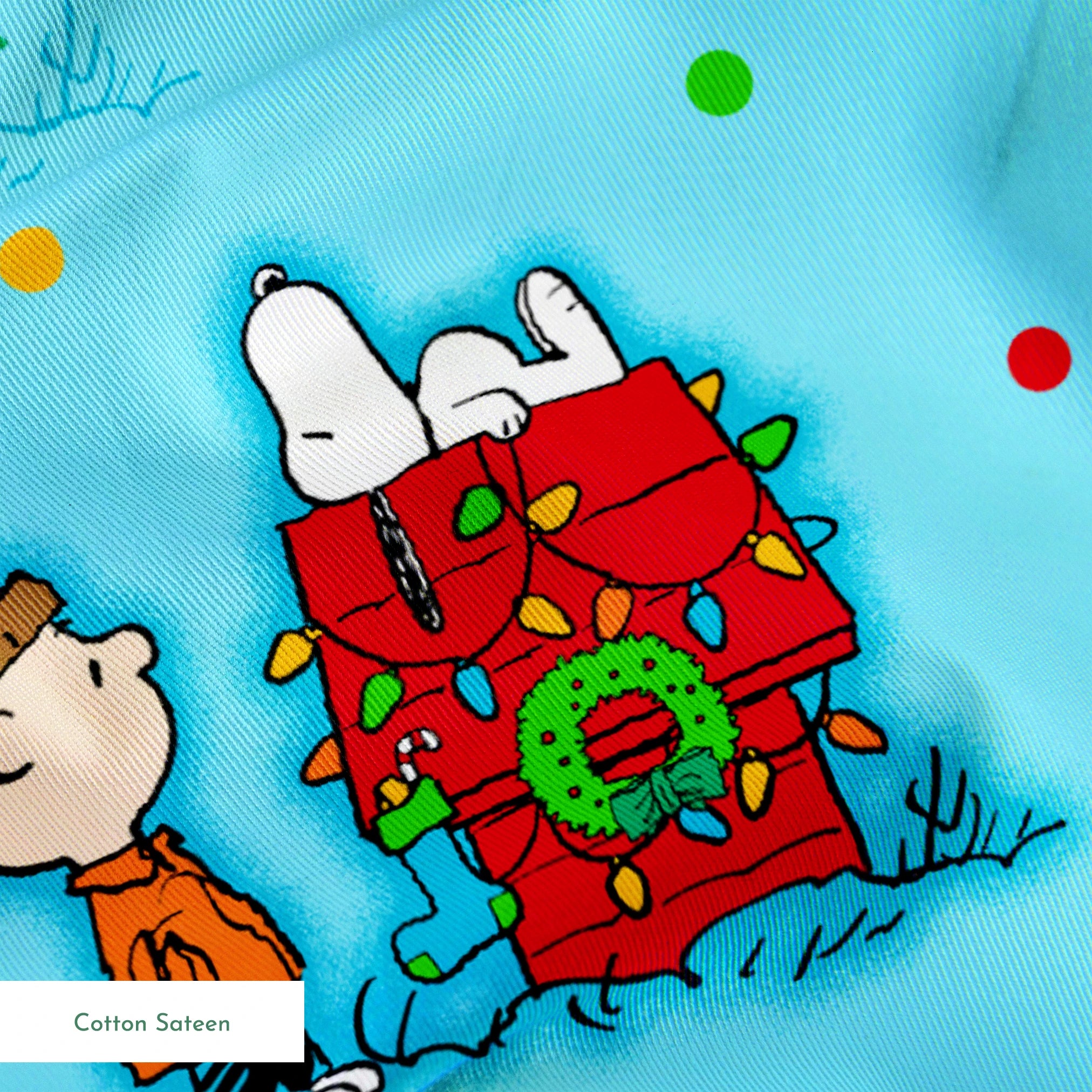 Peanuts Christmas pattern with Snoopy, Charlie Brown, and friends decorating trees on light blue background springs sateen texture