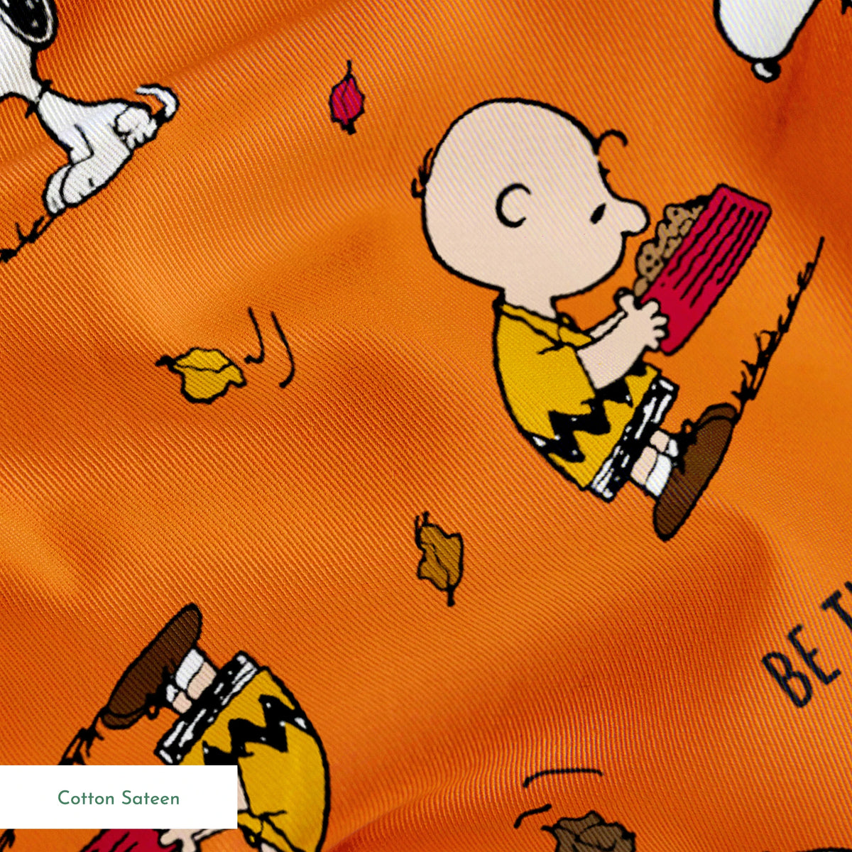 Peanuts characters on orange background with autumn leaves and "Be Thankful" text pattern springs sateen texture