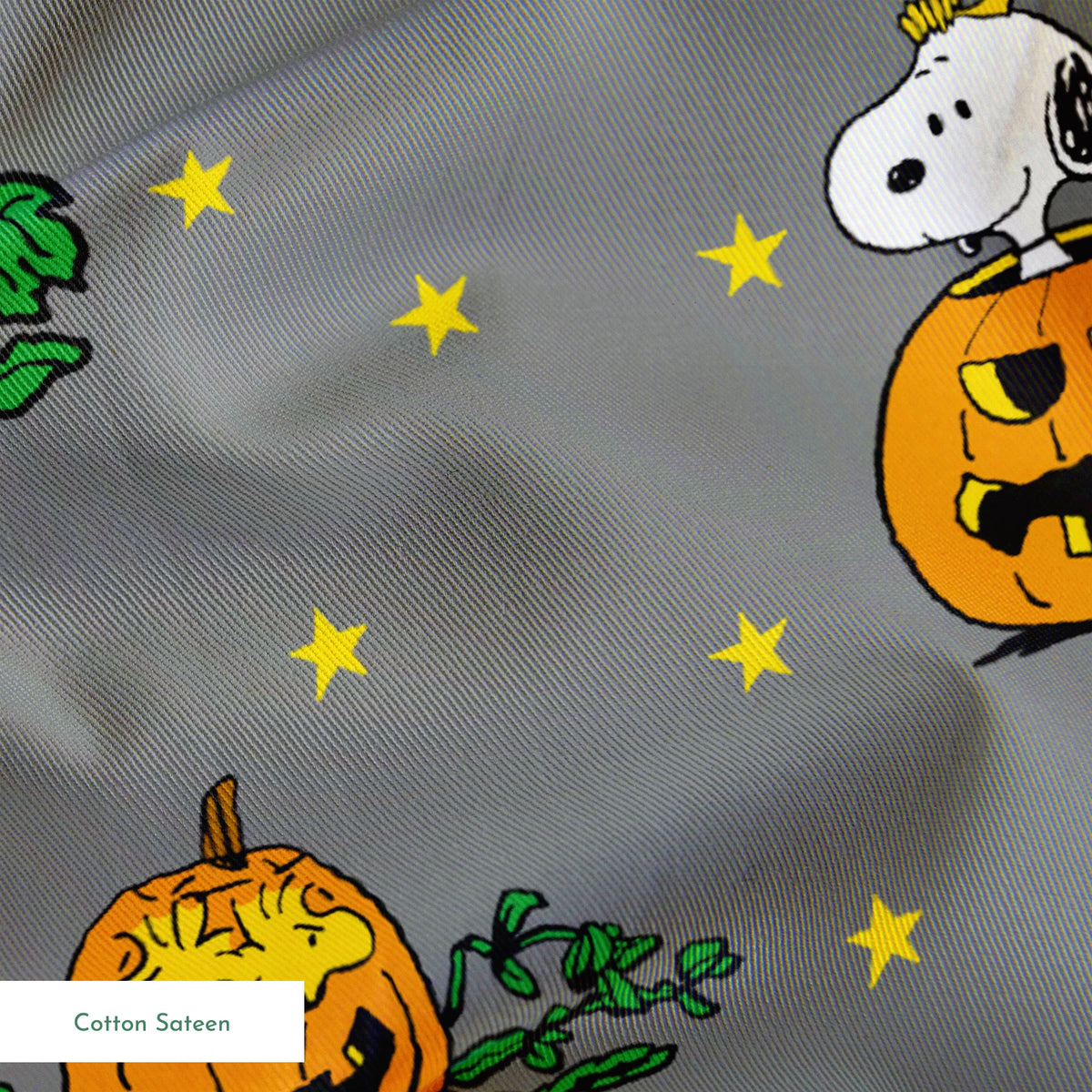 Peanuts Halloween pattern with Snoopy on pumpkins, Peanuts characters in pumpkin patches, and yellow stars on gray background. springs sateen texture