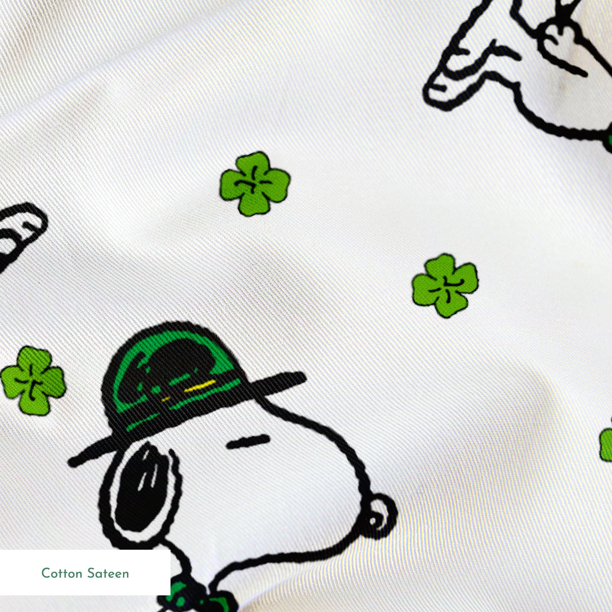 Cartoon Snoopy wearing green hat with shamrocks scattered across white background springs sateen texture
