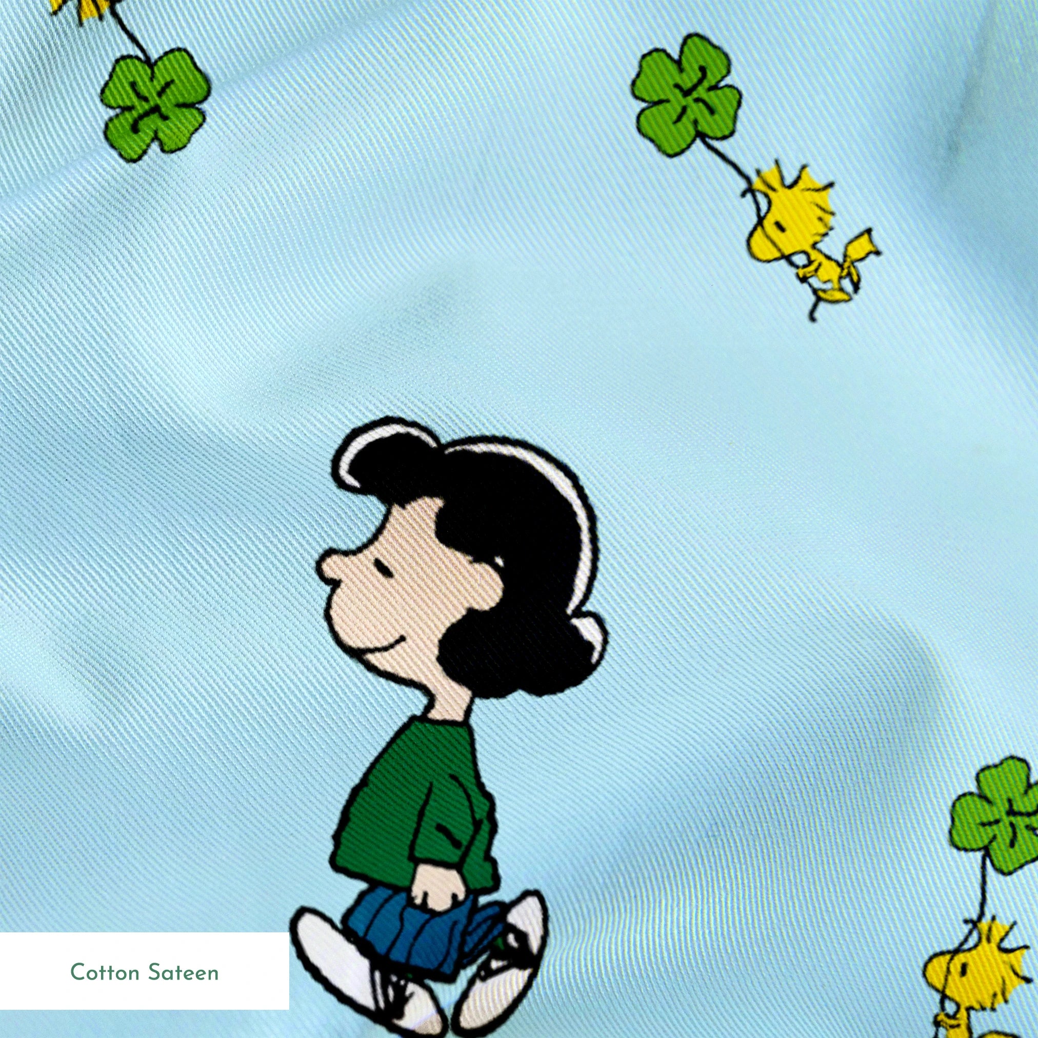 Peanuts cartoon characters on light blue background with clovers springs sateen texture