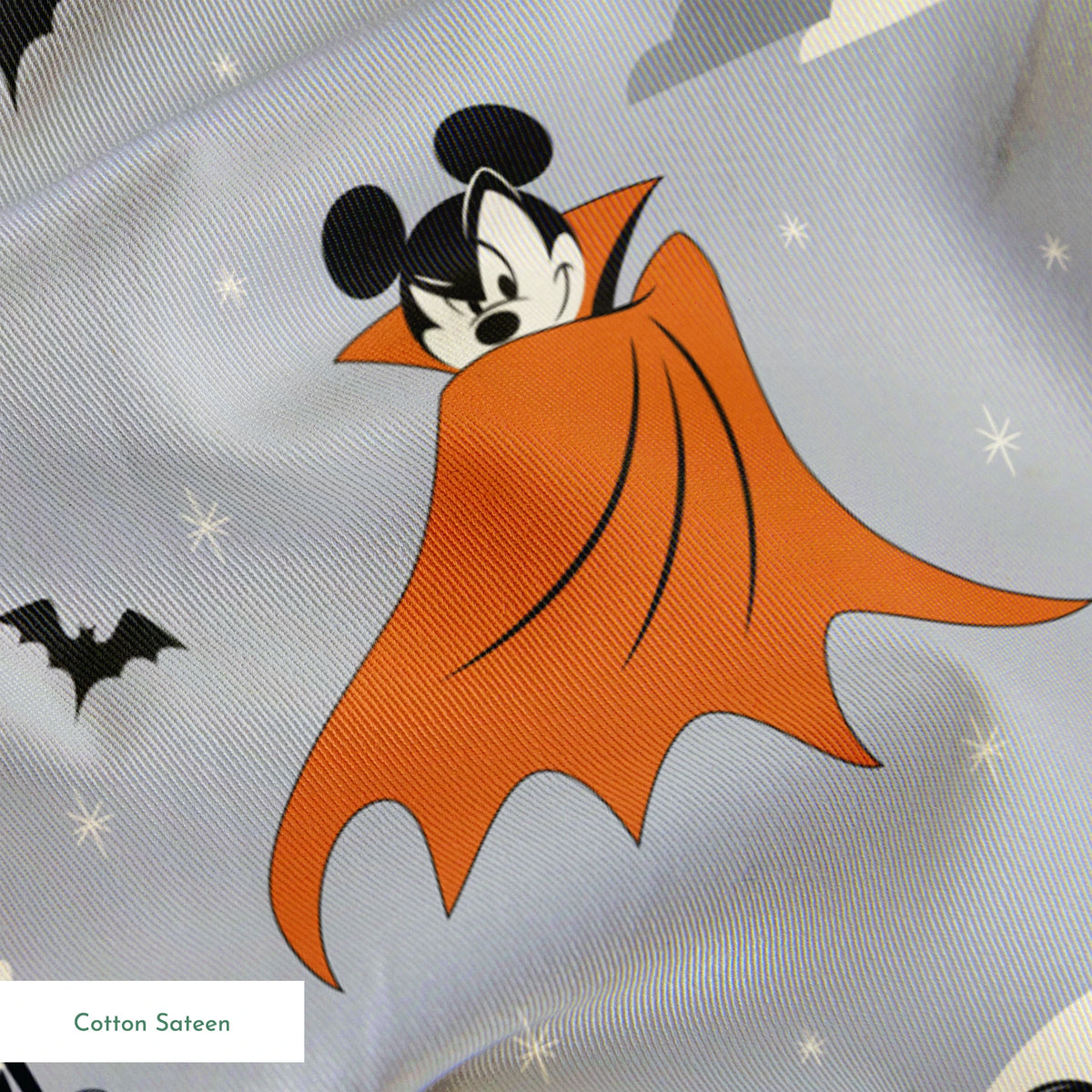 Mickey and Minnie Mouse in Halloween costumes on gray background with bats and moons, orange capes and spooky theme. springs sateen texture
