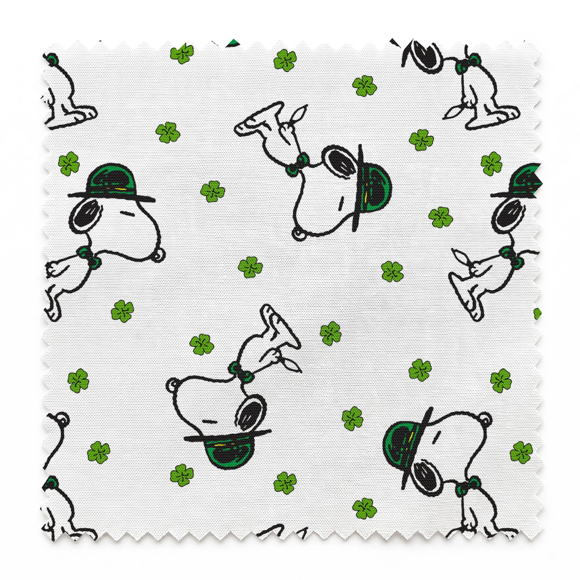 Cartoon Snoopy wearing green hat with shamrocks scattered across white background springs swatch pinked